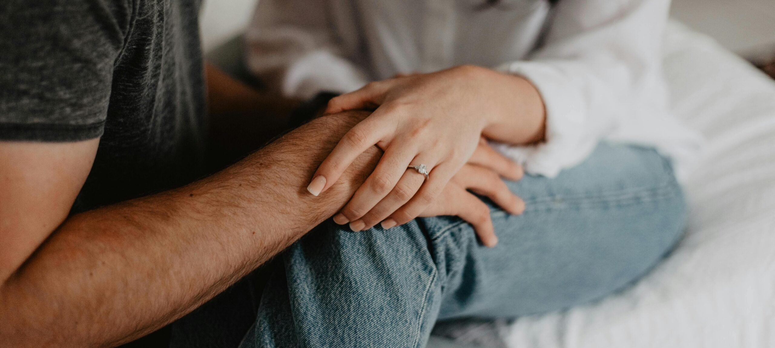 husband and wife sitting on bed holding hands