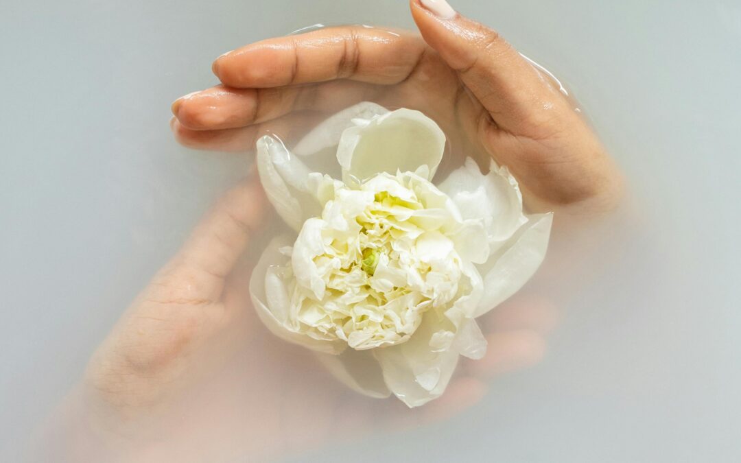 White flower in women's hand, in water - supporting a healthy menstrual cycle through self care